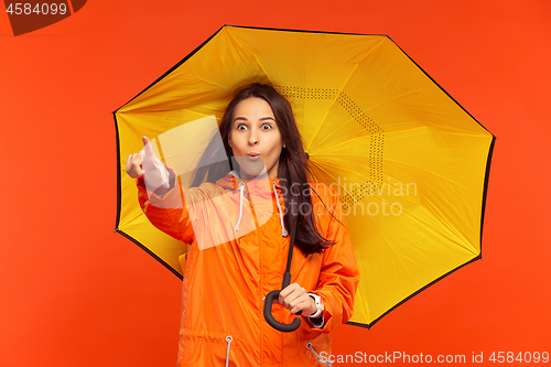 Image of The young girl posing at studio in autumn jacket isolated on red