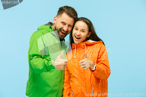 Image of The young surprised couplel posing at studio in autumn jackets isolated on blue