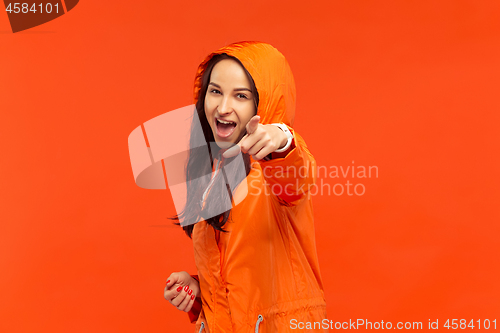 Image of The young girl posing at studio in autumn jacket isolated on red