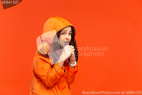 Image of The young girl posing at studio in autumn jacket isolated on red