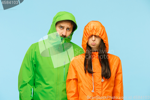 Image of The young couplel posing at studio in autumn jackets isolated on blue