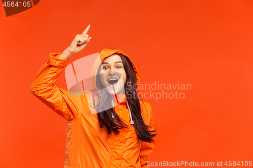 Image of The young girl posing at studio in autumn jacket isolated on red