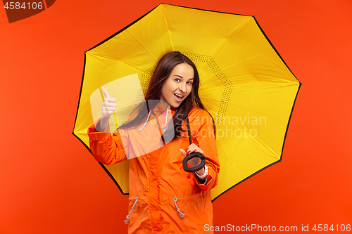 Image of The young girl posing at studio in autumn jacket isolated on red