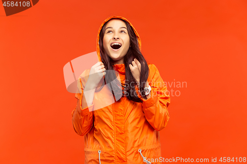 Image of The young girl posing at studio in autumn jacket isolated on red