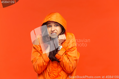 Image of The young girl posing at studio in autumn jacket isolated on red