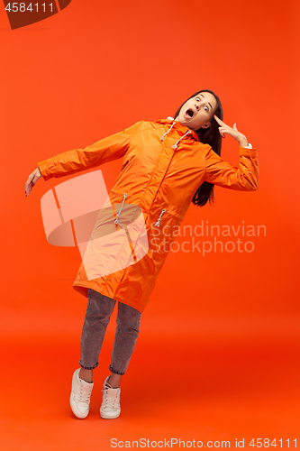 Image of The young girl posing at studio in autumn jacket isolated on red