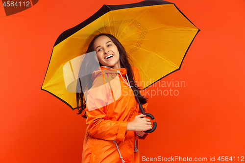 Image of The young girl posing at studio in autumn jacket isolated on red