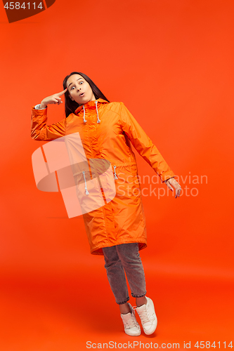 Image of The young girl posing at studio in autumn jacket isolated on red