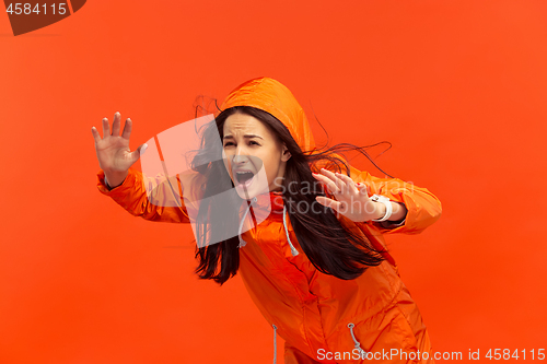 Image of The young girl posing at studio in autumn jacket isolated on red