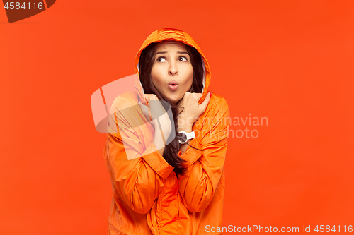 Image of The young girl posing at studio in autumn jacket isolated on red