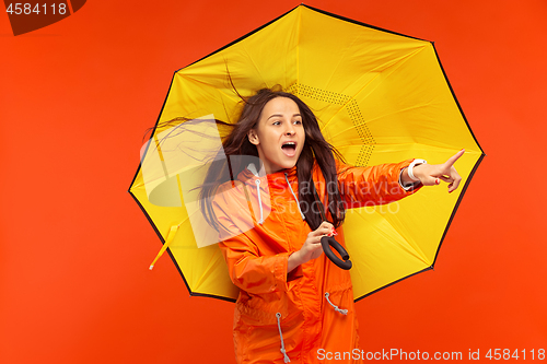 Image of The young girl posing at studio in autumn jacket isolated on red