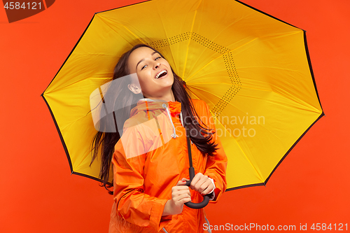 Image of The young girl posing at studio in autumn jacket isolated on red