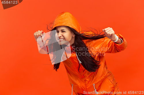 Image of The young girl posing at studio in autumn jacket isolated on red