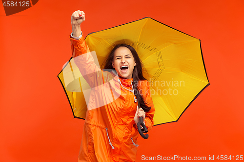 Image of The young girl posing at studio in autumn jacket isolated on red