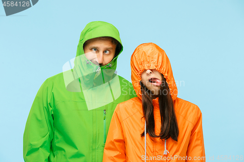 Image of The young couplel posing at studio in autumn jackets isolated on blue