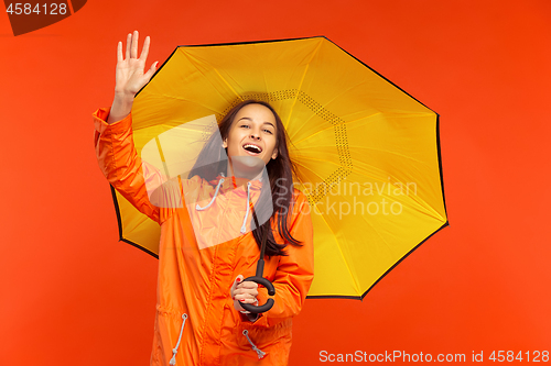 Image of The young girl posing at studio in autumn jacket isolated on red