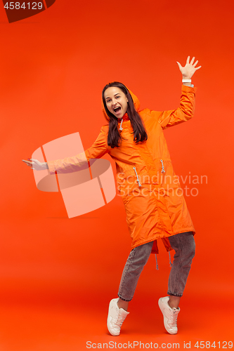 Image of The young girl posing at studio in autumn jacket isolated on red