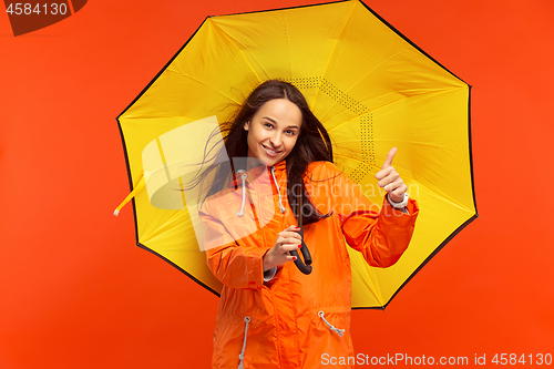 Image of The young girl posing at studio in autumn jacket isolated on red