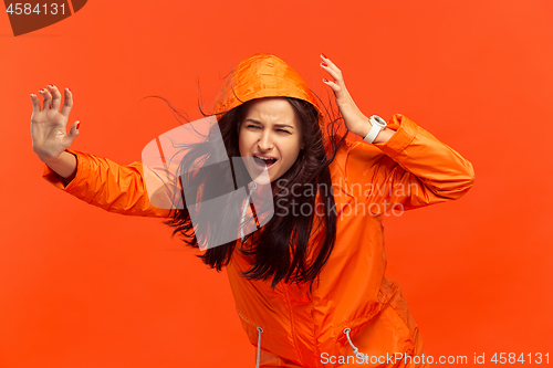 Image of The young girl posing at studio in autumn jacket isolated on red