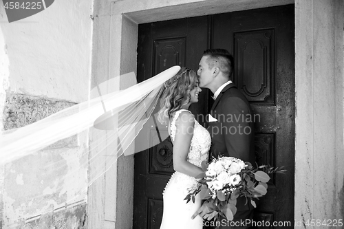 Image of The kiss. Groom kisses bride on forehead in front of church portal.