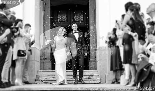 Image of Newlyweds exiting the church after the wedding ceremony, family and friends celebrating their love with the shower of soap bubbles, custom undermining traditional rice bath