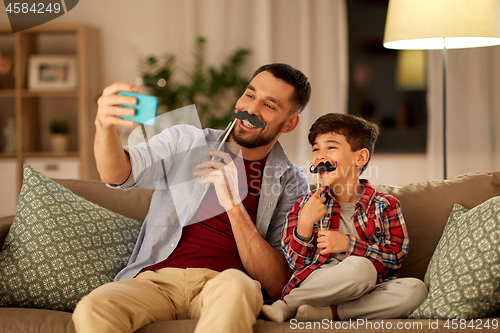 Image of father and son taking selfie at home