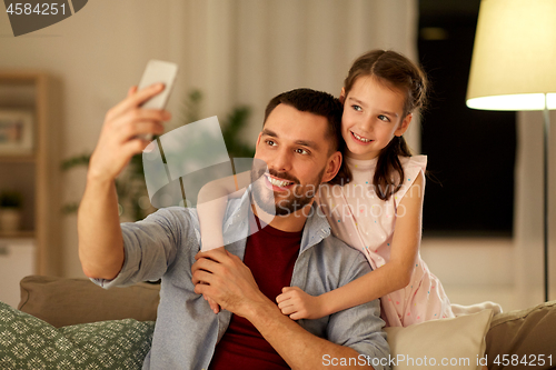 Image of father and daughter taking selfie at home