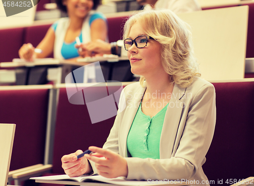 Image of student girl writing to notebook in lecture hall