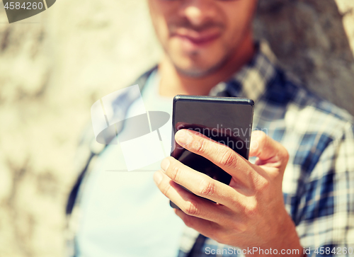 Image of man with smartphone texting message outdoors