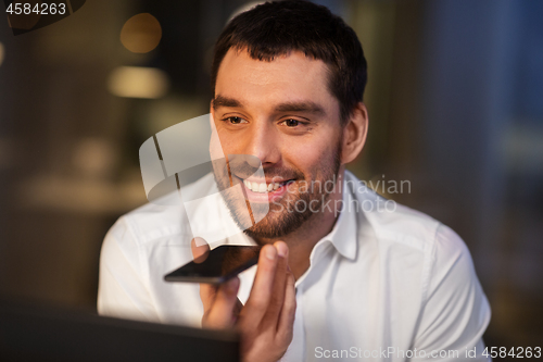 Image of businessman recording voice message on smartphone