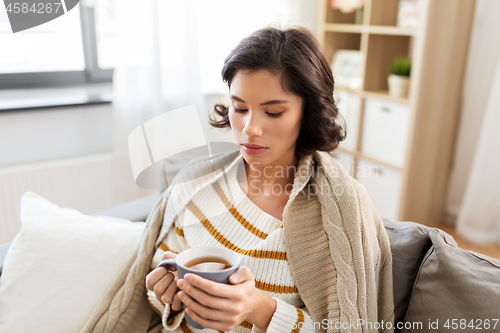 Image of sad sick young woman drinking hot tea at home