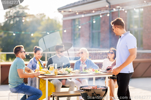 Image of man grilling meat on bbq at rooftop party