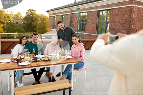 Image of happy friends photographing at rooftop party