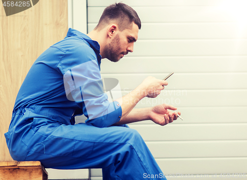 Image of auto mechanic smoking cigarette at car workshop