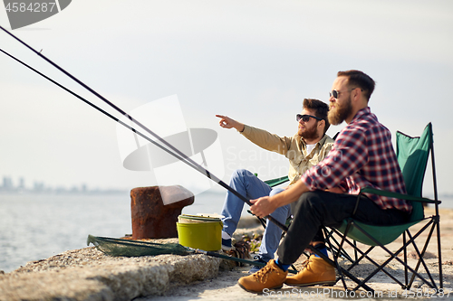 Image of happy friends with fishing rods on pier