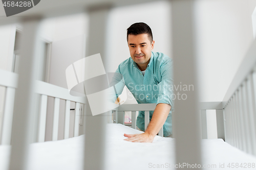 Image of father arranging baby bed with mattress at home