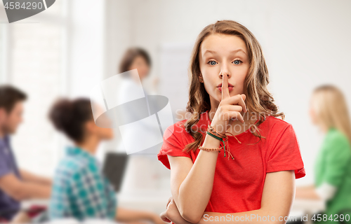 Image of teenage girl in red t-shirt with finger on lips