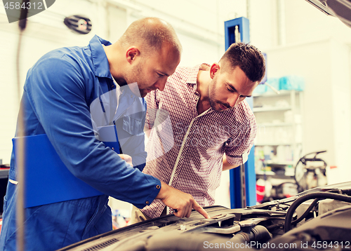 Image of auto mechanic with clipboard and man at car shop