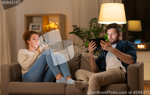 Image of couple with tablet computer and smartphone at home