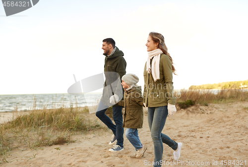 Image of happy family walking along autumn beach