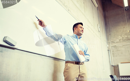 Image of teacher pointing marker to white board at lecture