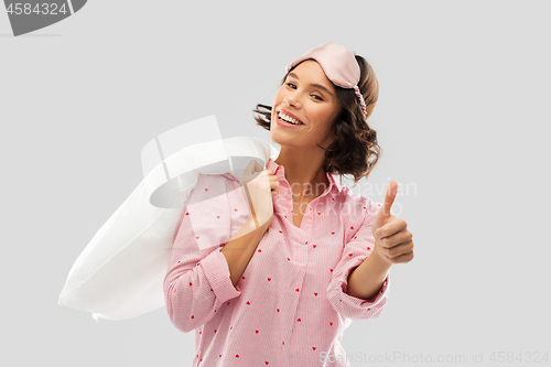 Image of woman with pillow in pajama showing thumbs up