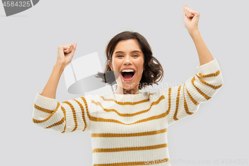 Image of happy young woman in pullover celebrating success