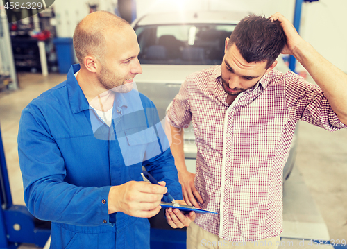 Image of auto mechanic with clipboard and man at car shop