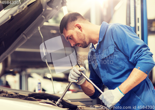 Image of mechanic man with wrench repairing car at workshop