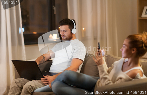 Image of couple with laptop and smartphone resting at home