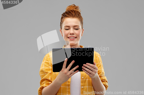 Image of red haired teenage girl using tablet computer