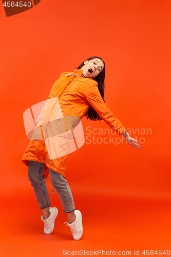 Image of The young girl posing at studio in autumn jacket isolated on red