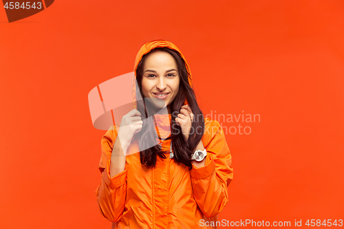 Image of The young girl posing at studio in autumn jacket isolated on red