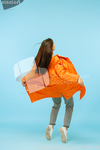 Image of The young girl posing at studio in autumn jacket isolated on blue